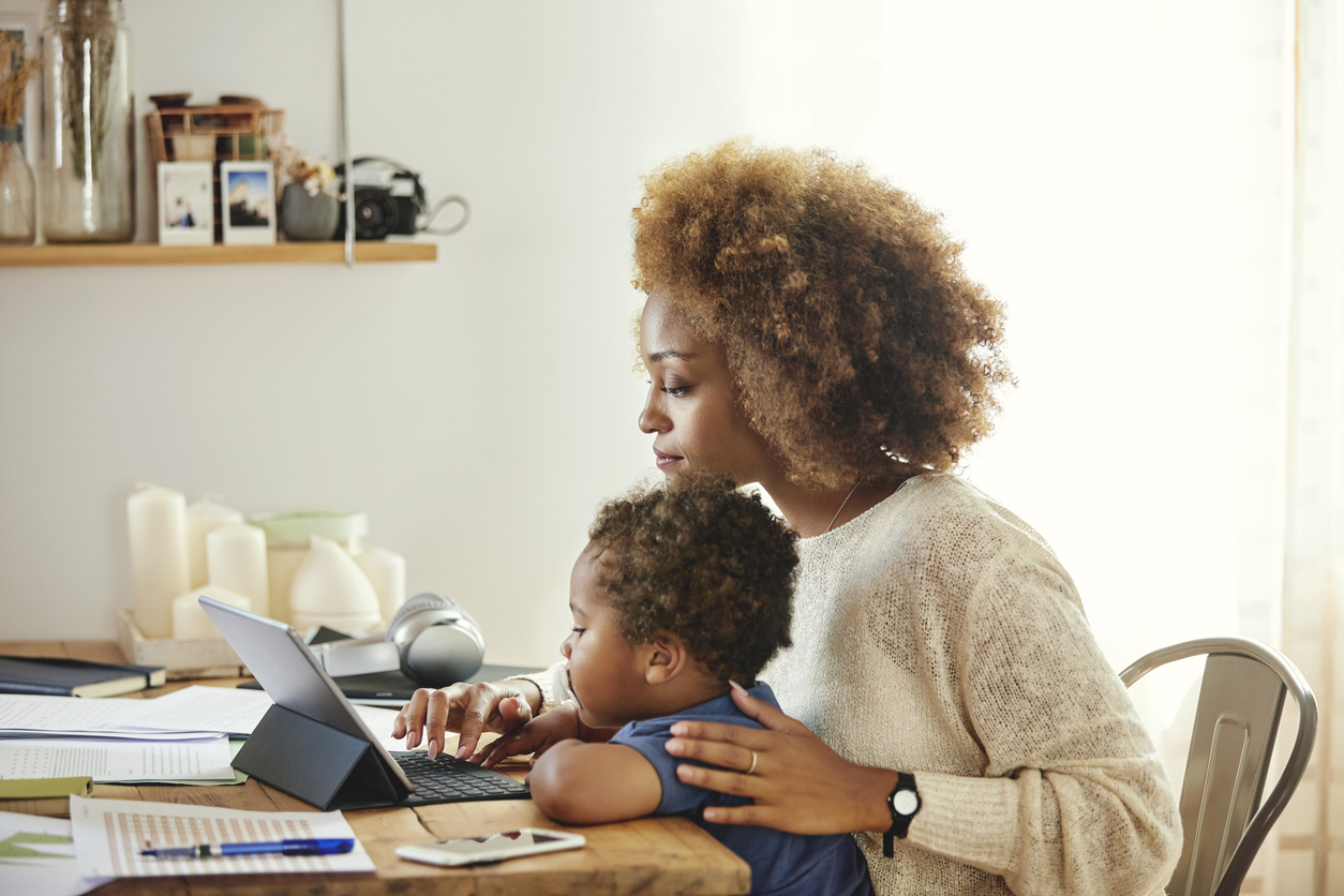 Business owner mom working with young son in her lap for Mother's Day